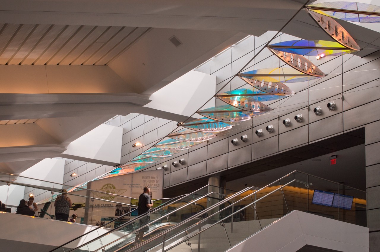 Ed Carpenter’s Wichita Dwight D. Eisenhower National Airport suspended sculpture Aloft makes an enormous aerial gesture in the space, springing from points along the architectural grid of the building, interacting with light from the skylight, and enveloping travelers on the escalators and balcony, as it soars from one end of the building to the other like an enormous abstract wing. | Image 3 | Ed Carpenter, Artist