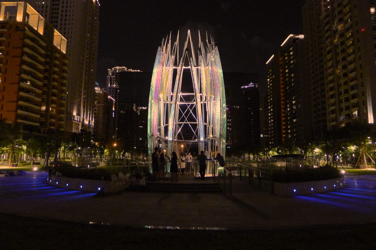 Night view shows carefully placed LED lighting dramatically illuminating the sculpture, Crocus. Taichung, Taiwan Civic Center monumental sculpture: Stainless Steel and Laminated Dichroic Glass | Image 1 | Ed Carpenter, Artist